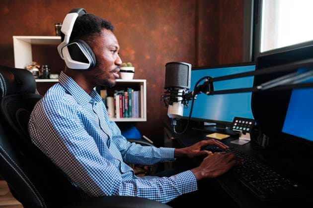 Creative Highlights Symbolbilder Male influencer talking through microphone while using computer during podcast model released Symbolfoto property released AGOF00099