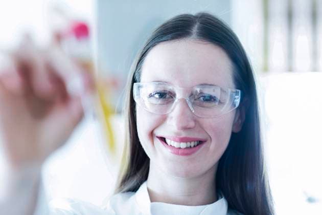 Smiling female scientist holding test tube in laboratory model released Symbolfoto property released SGF02802