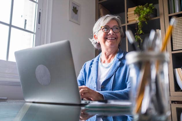 Happy businesswoman looking away while working with laptop at home model released Symbolfoto property released SIPF02304