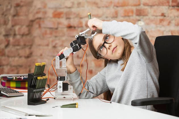 Girl doing scientific experiment on robotic arm at table model released Symbolfoto property released DHEF00616