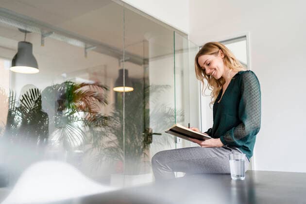 IMAGO Creative: Kreative Renaissance -- der junge Entrepreneur Smiling female entrepreneur reading diary while sitting on conference table in office model released Symbolfoto property released DIGF15009