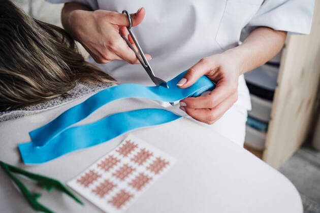 Female physiotherapist cutting elastic therapeutic tape model released Symbolfoto property released EBBF03259