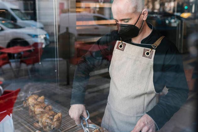 Mature male restaurant owner cutting roast chicken meat in commercial kitchen model released Symbolfoto property released EGAF02217
