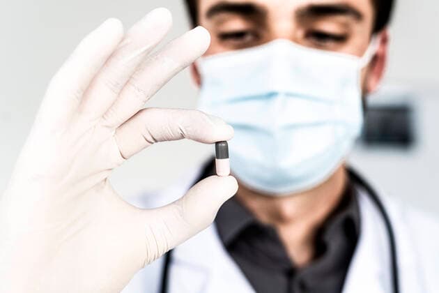 Male doctor wearing protective face mask holding capsule model released Symbolfoto property released GIOF12262