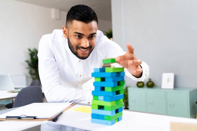 Smiling male entrepreneur holding toy block at office model released Symbolfoto property released GIOF12302