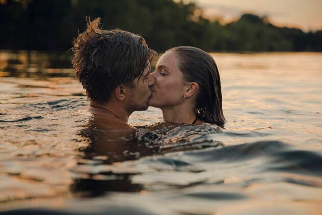 Young couple swimming in lake, kissing at sunset model released Symbolfoto GUSF02361