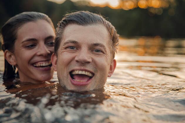 Young couple swimming in lake at sunset model released Symbolfoto GUSF02365