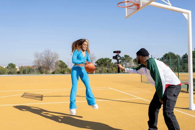 Happy male and female vlogging with basketball on sports court model released Symbolfoto JCCMF01721