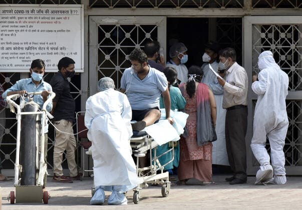 NEW DELHI, INDIA - APRIL 27: Medical workers in personal protective equipment (PPE) with a covid patients on oxygen support shifted the Covid-19 ward at Lok Nayak Jai Prakash (LNJP) on April 27, 2021 in New Delhi, India. As Covid-19 cases continued to surge in Delhi with over 98,264 active cases people are struggling to get hospital beds, ventilators, oxygen cylinders, injections and medicines with the health infrastructure in the state almost stretched to its limit. (Photo By Sonu Mehta Hindustan Times) As COVID Cases Surge, Indian Hospitals Struggle With Shortage Of Beds