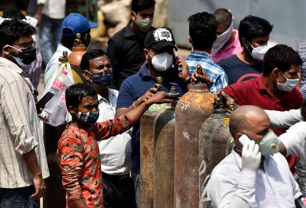 NEW DELHI, INDIA - APRIL 27: People wait to refill empty oxygen cylinders at a plant in Naraina, on April 27, 2021 in New Delhi, India. As Covid-19 cases continued to surge in Delhi with over 98,264 active cases people are struggling to get hospital beds, ventilators, oxygen cylinders, injections and medicines with the health infrastructure in the state almost stretched to its limit. (Photo by Sanjeev Verma Hindustan Times) India Faces Oxygen Crisis As Covid-19 Cases Mount