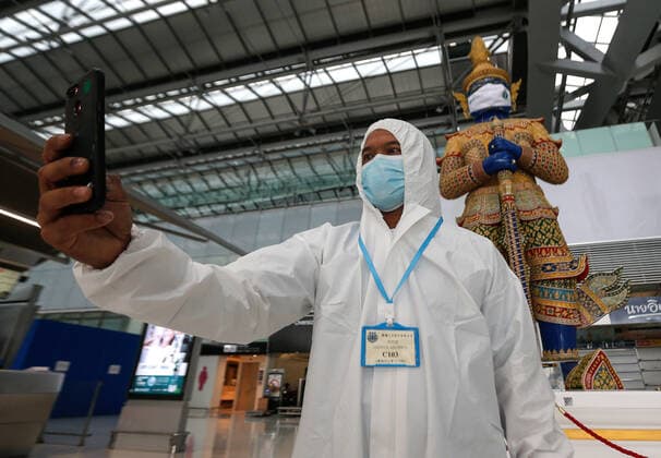 April 28, 2021, Bangkok, Thailand: A passenger wearing personal protective equipment suite (PPE) takes a selfie next to a statue wearing a mask, at Suvarnabhumi airport..Ministry of Public Health and the Airport Operation Centre set up a new vaccination centre to remedy the Covid 19 emergency situation and efficiency of vaccination for aviation-related personnel. Bangkok Thailand - ZUMAs197 20210428_zaa_s197_032 Copyright: xChaiwatxSubprasomx