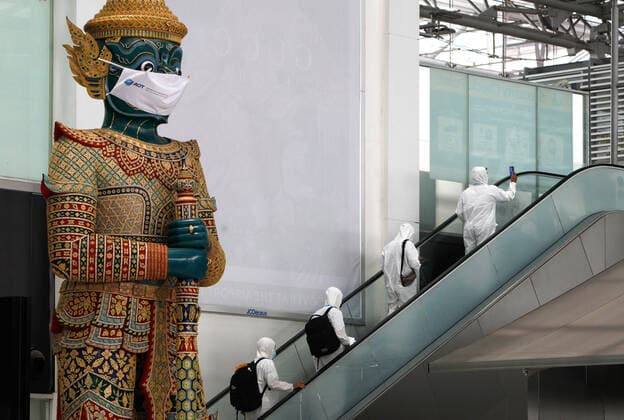 April 28, 2021, Bangkok, Thailand: Passengers wearing personal protective equipment suite (PPE) walk towards the departure international gate passed a giant statue wearing a face mask, at Suvarnabhumi airport..Ministry of Public Health and the Airport Operation Centre set up a new vaccination centre to remedy the Covid 19 emergency situation and efficiency of vaccination for aviation-related personnel. Bangkok Thailand - ZUMAs197 20210428_zaa_s197_042 Copyright: xChaiwatxSubprasomx