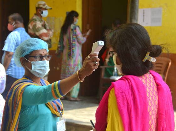 India: Last Phase of voting at West Bengal Assembly Election 2021 A vote worker taking body temperature by thermal gun before entering the voting booth. Calcutta West Bengal India Copyright: AnubrataxMondal