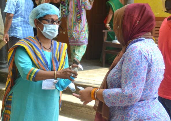 India: Last Phase of voting at West Bengal Assembly Election 2021 Government Employee giving Hand Sanitizer to a lady Voter to prevent Covid19 during the periods of West Bengal Assembly Election 2021 Calcutta West Bengal India Copyright: AnubrataxMondal