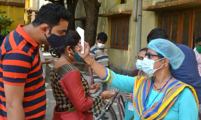 India: Last Phase of voting at West Bengal Assembly Election 2021 A vote worker taking body temperature by thermal gun before entering the voting booth. Calcutta West Bengal India Copyright: AnubrataxMondal