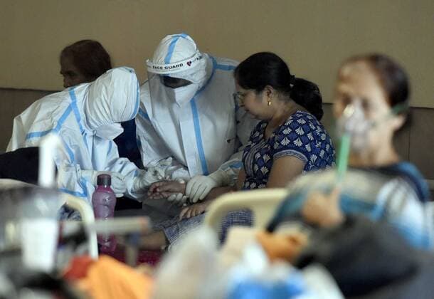NEW DELHI, INDIA - APRIL 29: Health workers in PPE checkup a Covid-19 patient to an isolation ward at the temporary Covid Care facility center attached to LNJP Hospital, at Shehnai Banquet on April 29, 2021 in New Delhi, India. As Covid-19 cases continued to surge in Delhi with over 97,977 active cases people are struggling to get hospital beds, ventilators, oxygen cylinders, injections and medicines with the health infrastructure in the state almost stretched to its limit. ( Photo by Sonu Mehta Hindustan Times) Temporary Covid Care Facility Centers In Delhi