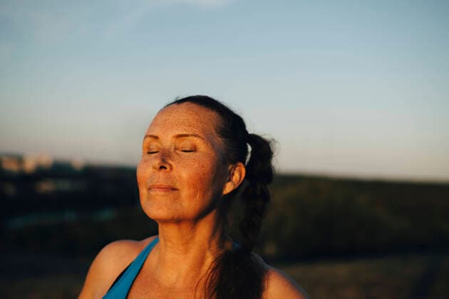 IMAGO Creative: Internationaler Frauenmonat, Gesundheit, Frauen in der Menopause Sportswoman with eyes closed against sky during sunset Sweden, Stockholm, model released Copyright: xMaskotx , MA86083