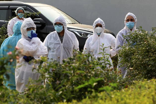April 30, 2021, New Delhi, India: Grieving family members wearing Personal Protective Equipment (PPE) look at the funeral pyre of their relative who lost his life due to the coronavirus Covid-19 disease during the mass cremation at Dwarka crematorium..The ongoing vaccination drive will open for 18-45 age group from May 01, 2021. India has recorded 386,452 new coronavirus infection cases and 3,498 death in the last 24 hours. New Delhi India - ZUMAs197 20210430_zaa_s197_089 Copyright: xNaveenxSharmax