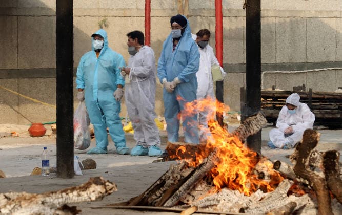 April 30, 2021, New Delhi, India: Grieving family members wearing Personal Protective Equipment (PPE) look at the funeral pyre of their relative who lost his life due to the coronavirus Covid-19 disease during the mass cremation at Dwarka crematorium..The ongoing vaccination drive will open for 18-45 age group from May 01, 2021. India has recorded 386,452 new coronavirus infection cases and 3,498 death in the last 24 hours. New Delhi India - ZUMAs197 20210430_zaa_s197_090 Copyright: xNaveenxSharmax