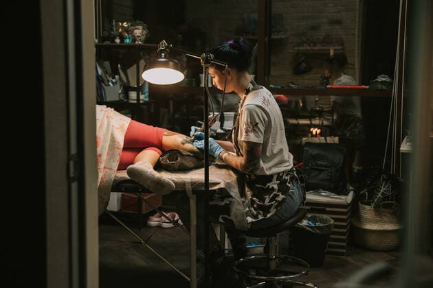 Portrait of a woman tattoo master showing a process of creation tattoo on a hand under the lamp light. CR_EVUV210502B-661880-01 ,model released, Symbolfoto