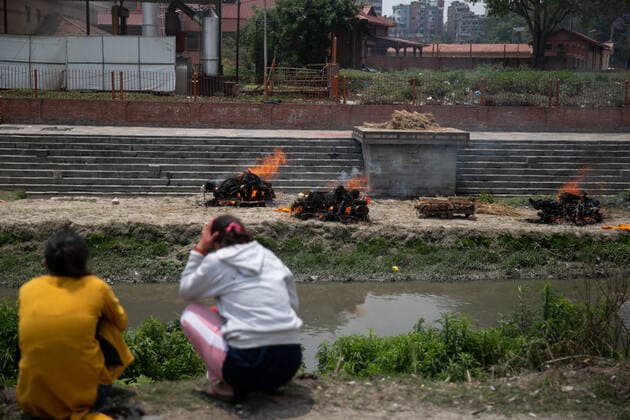 May 11, 2021, Kathmandu, Nepal: Family members watch across the Bagmati river as Nepalese men wearing protective suits cremate the bodies of COVID-19 victims near Bank of Bagmati river at the premises of Pashupatinath temple..Electronic crematorium situated in Pashupati is congested with COVID-19 death bodies arriving for cremation. As there is no space inside the crematorium due to limited capacity death bodies of the deceased are being burned near the bank of Bagmati River at the Premises of Pashupatinath temple. Kathmandu Nepal - ZUMAs197 20210511_zaa_s197_001 Copyright: xPrabinxRanabhatx