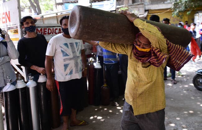 Family members of COVID-19 patients wait outside an oxygen-filling center to refill their empty cylinders, as demand for the gas rises due to spike in coronavirus cases, in New Delhi, India on Monday, May, 3, 2021.  DEL20210503055 Abhishek