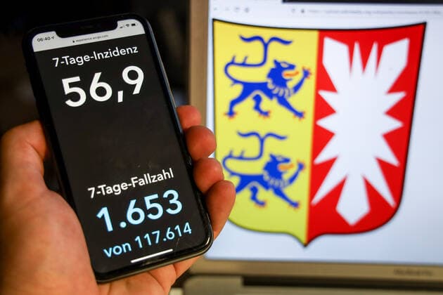 Coronavirus in Deutschland - Covid-19-Dashboard des Robert Koch-Institut DEU, Deutschland, Schleswig-Holstein, 04.05.2021: Die 7-Tage-Inzidenz für das Bundesland (Fälle letzte 7 Tage 100.000 EW) wird auf einem iPhone angezeigt, im Hintergrund das Landeswappen