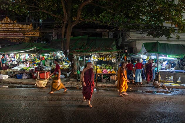 Night street scenes of Yangon, Myanmar YANGON, MYANMAR - January 08, 2018: Monk walking in front of street stalls in the night. Yangon Myanmar *** Nächtliche Straßenszenen von Yangon, Myanmar YANGON, MYANMAR 08. Januar 2018 Mönch geht vor Straßenständen in der Nacht Yangon Myanmar Copyright: xoffenberg@gmx.dex