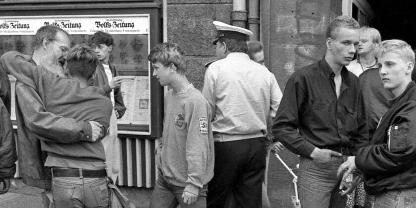 Straßenfotografie in der Wendezeit - Szene vor einem Schaukasten einer Tageszeitung in der Doberaner Straße - 12.04.1990 - Rostock: Es gab zu DDR-Zeiten kaum Stadtreporter, die das Leben auf der Straße unverfälscht abbildeten. Schnell konnte sie in die Schublade - Stasi oder Paparazzi - geraten, obwohl es sich bei den Motiven um Zeitgeschichte handelt. Heute ist die Street Photography oder auch Straßenfotografie als Genre anerkannt. Dennoch sind berechtigte Interessen der abgebildeten Personen wie das Recht am eigenen Bild und die Persönlichkeitsrechte zu wahren. Kein leichtes Unterfangen. Rostock Mecklenburg-Vorpommern Deutschland *** Street photography at the time of reunification Scene in front of a showcase of a daily newspaper i