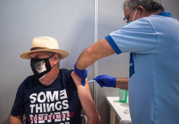May 5, 2021, Malaga, Spain: A man wearing a face mask as a precaution against the spread of covid-19 is being vaccinated by a health worker inside a cubicle during a massive vaccination at Fair and Congresses Palace..Health regional authorities have retimed again the vaccination with doses of Pfizer BioNTech inside large and secure places following all protective measures, as part of massive vaccination One million plan after the announcement of Andalusian government to inoculate around 600.000 vaccines during the week. Malaga Spain - ZUMAs197 20210505_zaa_s197_025 Copyright: xJesusxMeridax