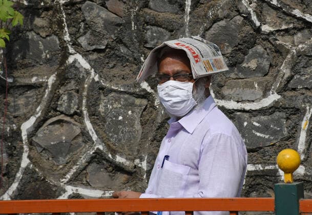 May 5, 2021, Mumbai, India: A man wearing a face mask is seen standing in a queue outside with a newspaper covering his head from the sun outside NESCO vaccination center in Mumbai..Vaccination drive which was stopped for people above 45 years of age last week started again with the availability of vaccine stock. Mumbai India - ZUMAs197 20210505_zaa_s197_029 Copyright: xAshishxVaishnavx