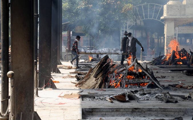 May 5, 2021, New Delhi, India: (EDITORS NOTE: Image depicts death).Family members carry the body of a relative who has died of the Covid-19 coronavirus disease as other funeral pyres are seen burning at Nigambodh Ghat crematorium in New Delhi..In India a third wave of the coronavirus is inevitable top scientific adviser said on Wednesday, 05 May, 2021. (A third wave of Covid-19 is inevitable given the amount of virus circulation, K. VijayRaghavan, Principal Scientific adviser to the Government of India has warned. He also added that there is a need to update vaccines to deal with new strains and mutations.) India records 382,146 new covid-19 cases and 3,572 deaths in the last 24 hours. New Delhi India - ZUMAs197 20210505_zaa_s197_149 Copyright: xNaveenxSharmax