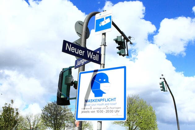 An einem Pfahl vor der Geschäftsstraße Neuer Wall in der Hamburger Innenstadt hängt ein Schild, das darauf hinweist, dass in diesem Bereich zu bestimmten Zeiten Maskenpflicht besteht. Altstadt Hamburg