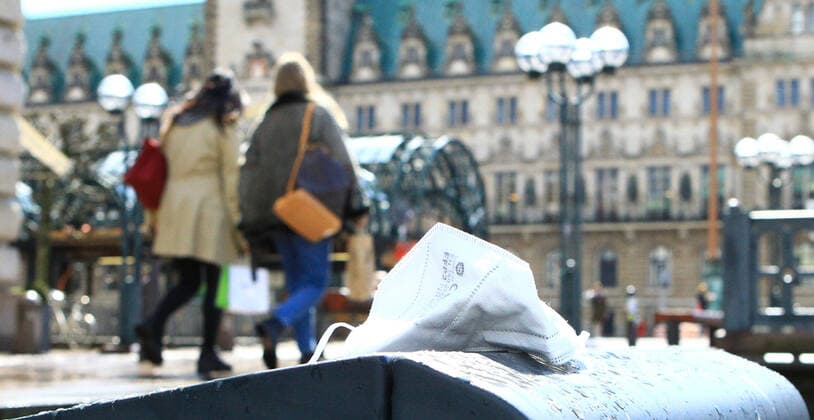 Eine Mund-Nasen-Maske liegt auf einem Müllbehälter am Reesendamm in der Hamburger Innenstadt. Im Hintergrund das Hamburger Rathaus. Altstadt Hamburg