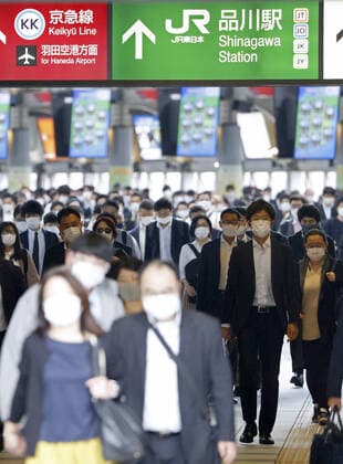 Commuters in Tokyo amid coronavirus pandemic People wearing face masks walk at Shinagawa Station in Tokyo during the morning commute on May 7, 2021, amid the coronavirus pandemic. 