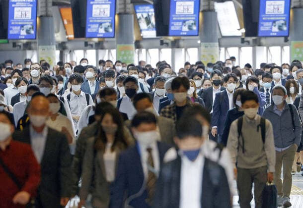 Commuters in Tokyo amid coronavirus pandemic People wearing face masks walk at Shinagawa Station in Tokyo during the morning commute on May 7, 2021, amid the coronavirus pandemic. 