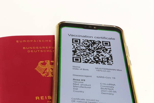 Symbolbild: Reisepass und ein digitaler Grüner Pass als Nachweis einer Impfung