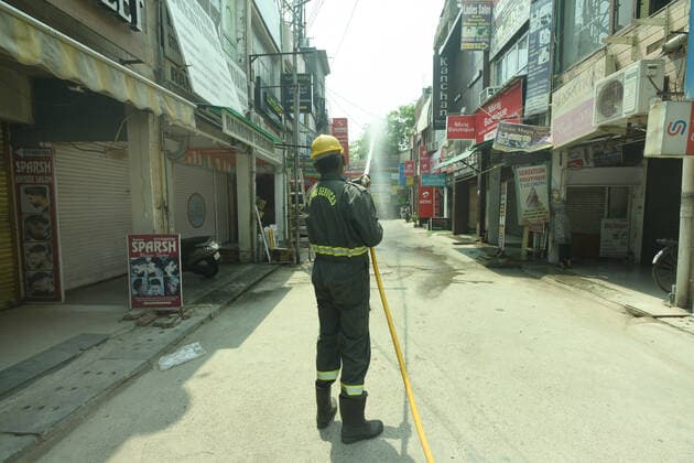 NOIDA, INDIA - MAY 7: Fire police personnel sanitize the premises at sector 25 market on May 7, 2021 in Noida, India. (Photo by Sunil Ghosh Hindustan Times) Sanitization Drive To Curb Covid Pandemic