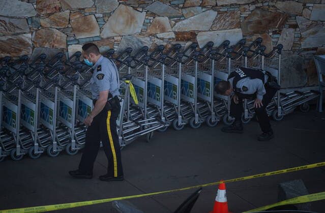 May 9, 2021, Richmond, BC, Canada: RCMP officers search around rows of luggage carts after a shooting outside the international departures terminal at Vancouver International Airport, in Richmond, B.C., Sunday, May 9, 2021. Richmond Canada  - ZUMAc35_ 20210509_zaf_c35_071 Copyright: xDarrylxDyckx