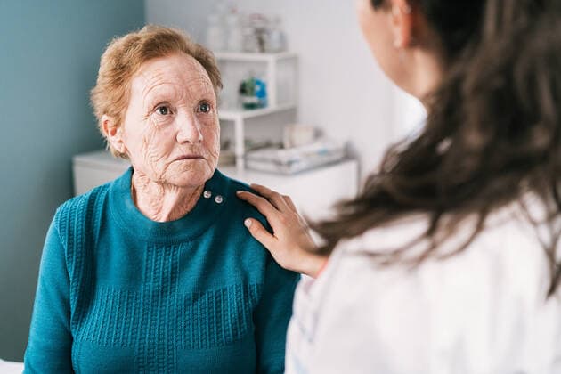 Crop anonymous doctor speaking with scared sad elderly woman while looking at each other during examination in hospital, Model released Copyright: xAlvaroxSanchezx MR