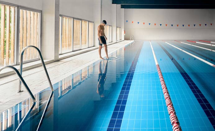 IMAGO Creative, Neujahr, Vorsätze, Sport IMAGO Creative: Reflexionen - Sport Side view of male athlete in swimming trunks standing against pool with lanes and pure water before workout, Model released, Property released Copyright: xCienxXxCienxStudiox MR