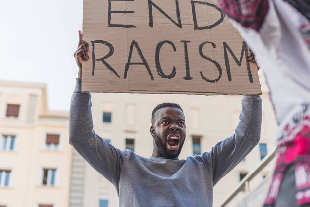 Low angle of African American male activist with End Racism poster screaming on city street during Black Lives Matter protest, Model released Copyright: xIvanxMorenox MR