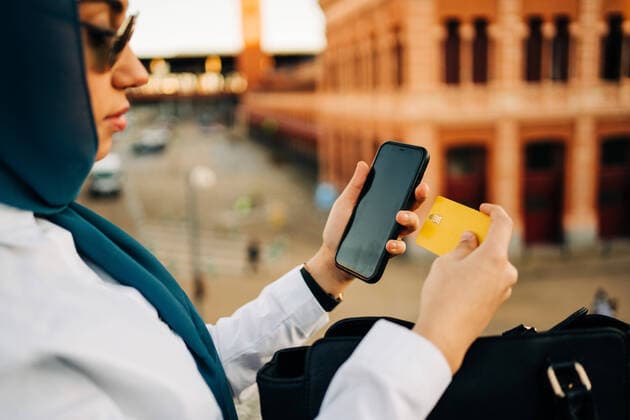IMAGO Creative: Digitale Welt, Social Commerce Side view of crop stylish Muslim female paying with plastic card for order during online shopping via smartphone in city Copyright: xJakexJakabx Model Released