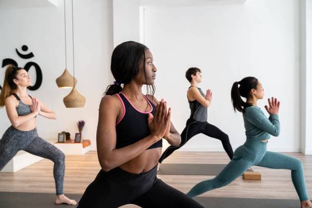 Side view of African American woman in company of diverse people practicing yoga in Warrior pose in studio, Model released, Property released Copyright: xJordixBatallerx MR