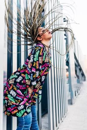 Side view of millennial female with long Afro braids leaning forward against wall on urban walkway, Model released, Property released Copyright: xJosexCarlosxGutierrezx MR