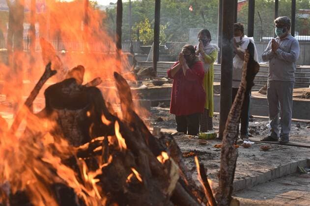 NEW DELHI, INDIA - MAY 11: Relatives carry the body of a Covid-19 victim for cremation, at Seema Puri crematorium on May 11, 2021 in New Delhi, India. Delhi has recorded 12,481 COVID-19 cases and 347 deaths over the last 24 hours, the positivity rate has dropped from 19 per cent to 17.7 per cent.(Photo by Raj K Raj Hindustan Times) Cremation Of Covid-19 Victims