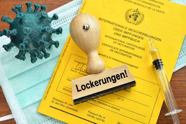 FOTOMONTAGE, Impfpass, Coronavirus-Modell, Impfspritze und Stempel mit der Aufschrift Lockerungen