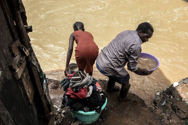 May 14, 2021, Nairobi, Kenya: NAIROBI, KENYA-MAY 14, 2021: A woman and her husband carry buckets of rain water from her house after her house was flooded during the heavy rains on May 13, 2021 in Nairobi, Kenya. Residents of Kibera Slums living close by Mutuine River were left homeless after the heavy floods that occured on May 13th, thursday night. Atleast four residents died including two young motorcyclist who were trying to cross over the river late at night whose copes were found nearby the ongoing bridge construction as hundreds of residents were also left homeless. Nairobi Kenya - ZUMAd156 20210514_zip_d156_010 Copyright: xDonwilsonxOdhiambox