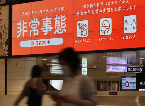 May 15, 2021, Osaka, Japan - People walk under a signage of a COVID-19 state of emergency in Osaka on Saturday, May 15, 2021. Japanese government announced to expand a COVID-19 state of emergency on May 14.  (160323364)
