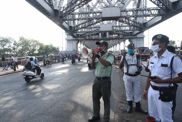 KOLKATA, INDIA - MAY 15: A police personnel speaks on a loudspeaker announcing a Covid-19 induced lockdown to come into effect tomorrow, at Howrah Bridge, on May 15, 2021 in Kolkata, India. The West Bengal government today announced that the state will go under a near lockdown for two weeks starting tomorrow. (Photo by Samir Jana Hindustan Times ) Lockdown In West Bengal For 2 Weeks From Tomorrow, Essential Services Allowed